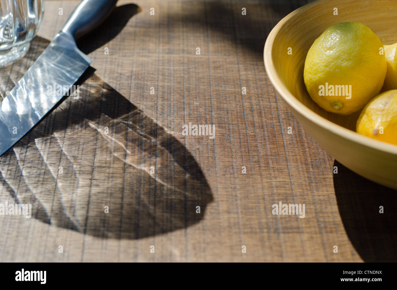 Un bol de citrons à côté d'un couteau et d'une verseuse sur un chêne platine prête à faire dans de la limonade sur un jour d'été. Banque D'Images