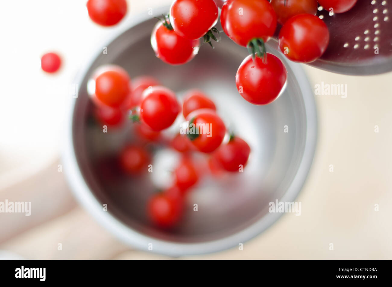 Tomates cerise mûre étant tombé, puis versez-la dans une passoire en métal argenté avec un fond blanc. Banque D'Images