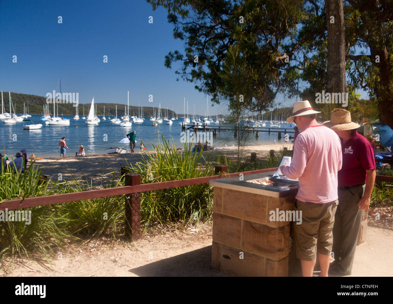 Barbecue sur la plage Australienne typique / barby avec deux hommes faire frire le bacon et les champignons Clareville Pittwater Sydney NSW Australie Banque D'Images