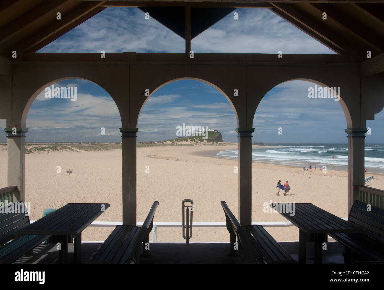 Plage de Nobbys et pointe vu à travers arcades de café avec deux surfeurs à pied de Newcastle mer Nouvelle Galles du Sud (NSW) Australie Banque D'Images