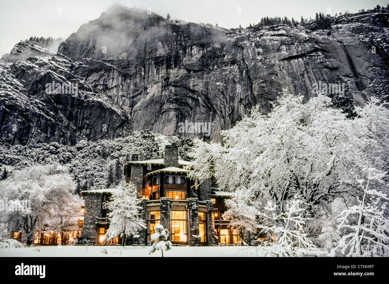 La lueur des lumières électriques à l'intérieur de l'historique 1927 Ahwahnee Hotel réchauffe une scène hivernale enneigée dans le parc national montagneux de Yosemite en Californie, aux États-Unis. Banque D'Images