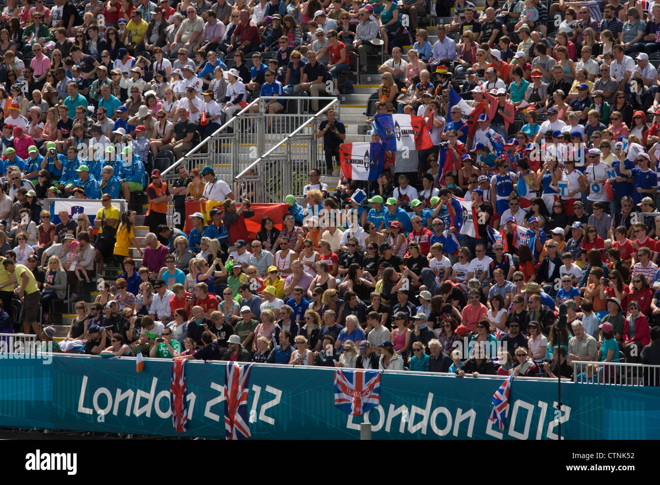 Fans français tenir leurs drapeaux nationaux entouré par des foules de supporters sportifs semblent en masse au cours de la chauffe de slalom en canoë à la Lee Valley White Water Centre, Nord-est de Londres, au jour 3 des Jeux Olympiques de 2012 à Londres. Banque D'Images