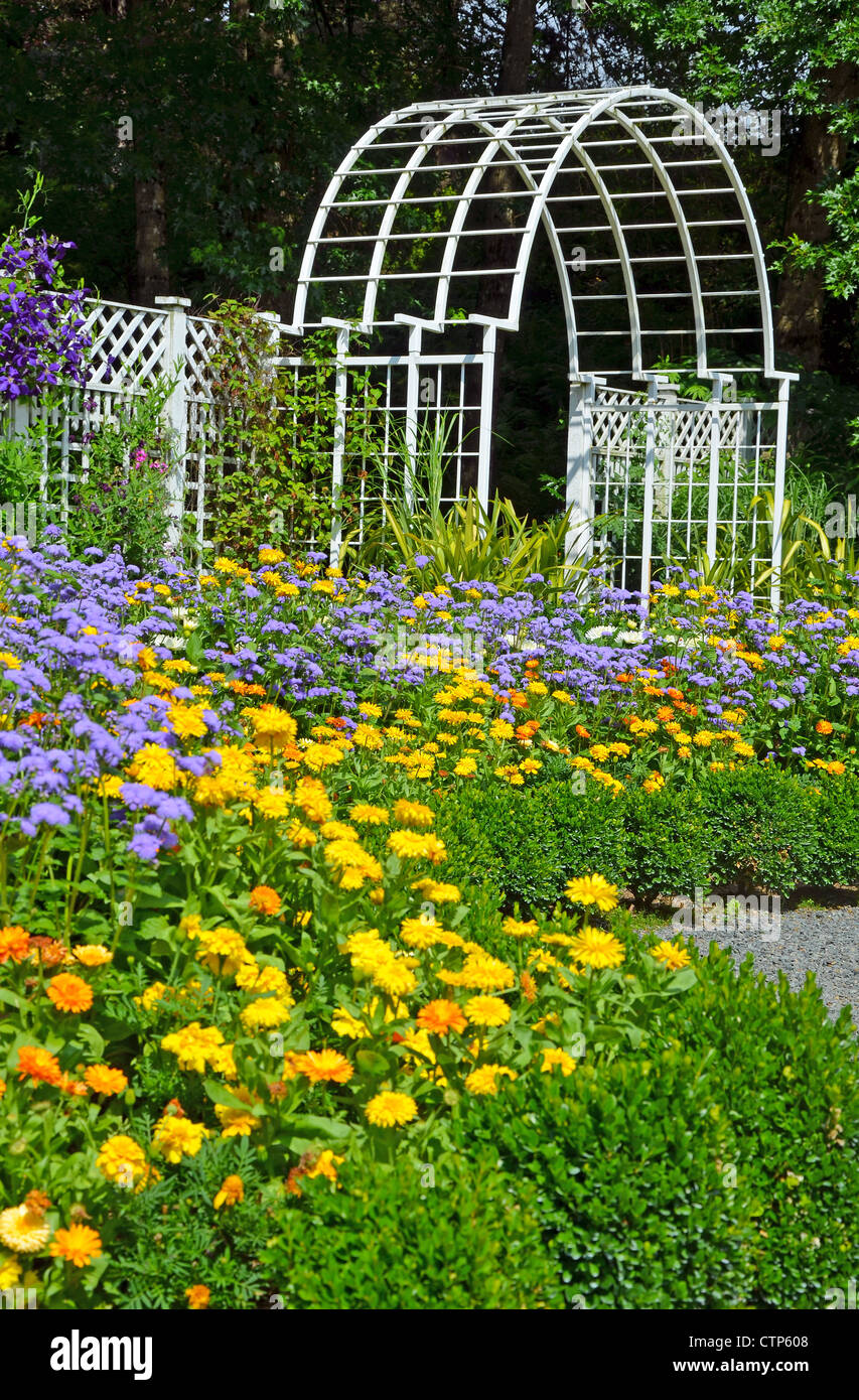 Jardin blanc archway entrée avec des fleurs colorées en premier plan Banque D'Images