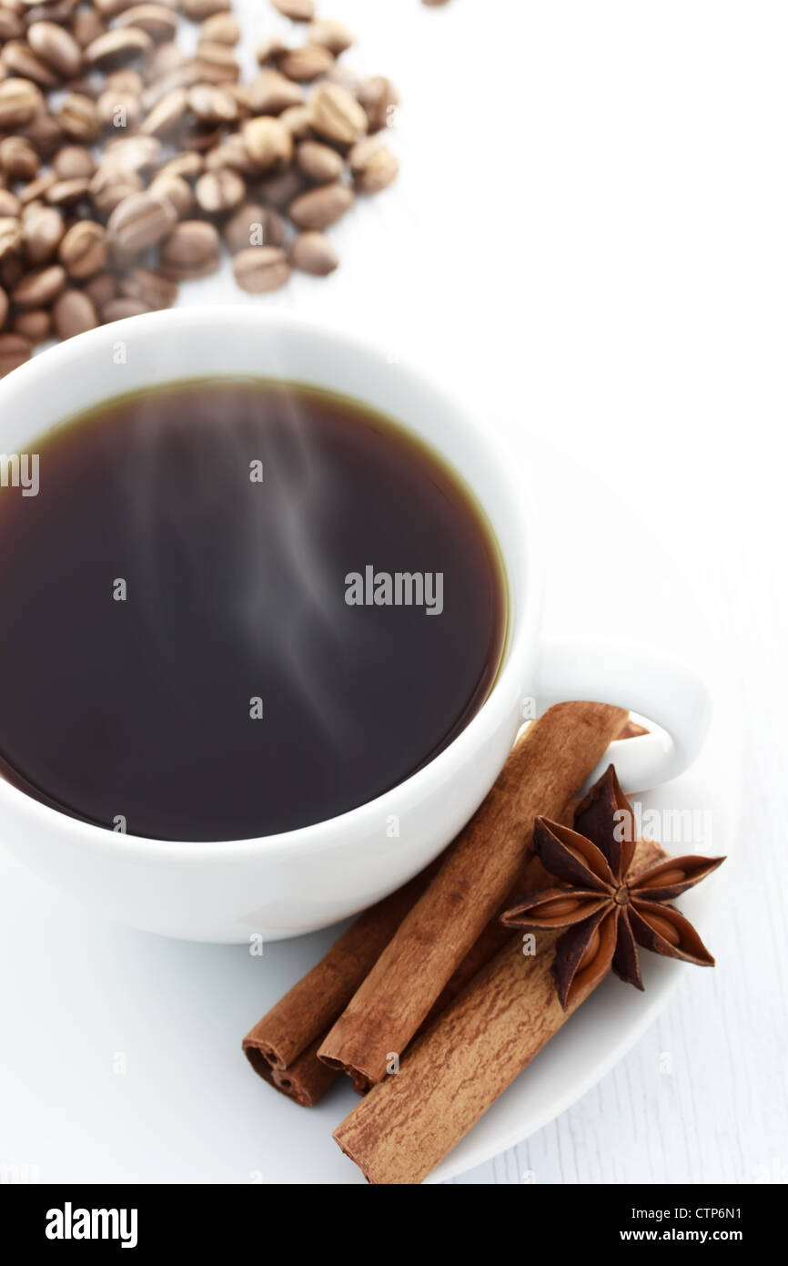 Tasse de café chaud avec des bâtons de cannelle, l'anis étoilé et les grains de café sur un tableau blanc Banque D'Images