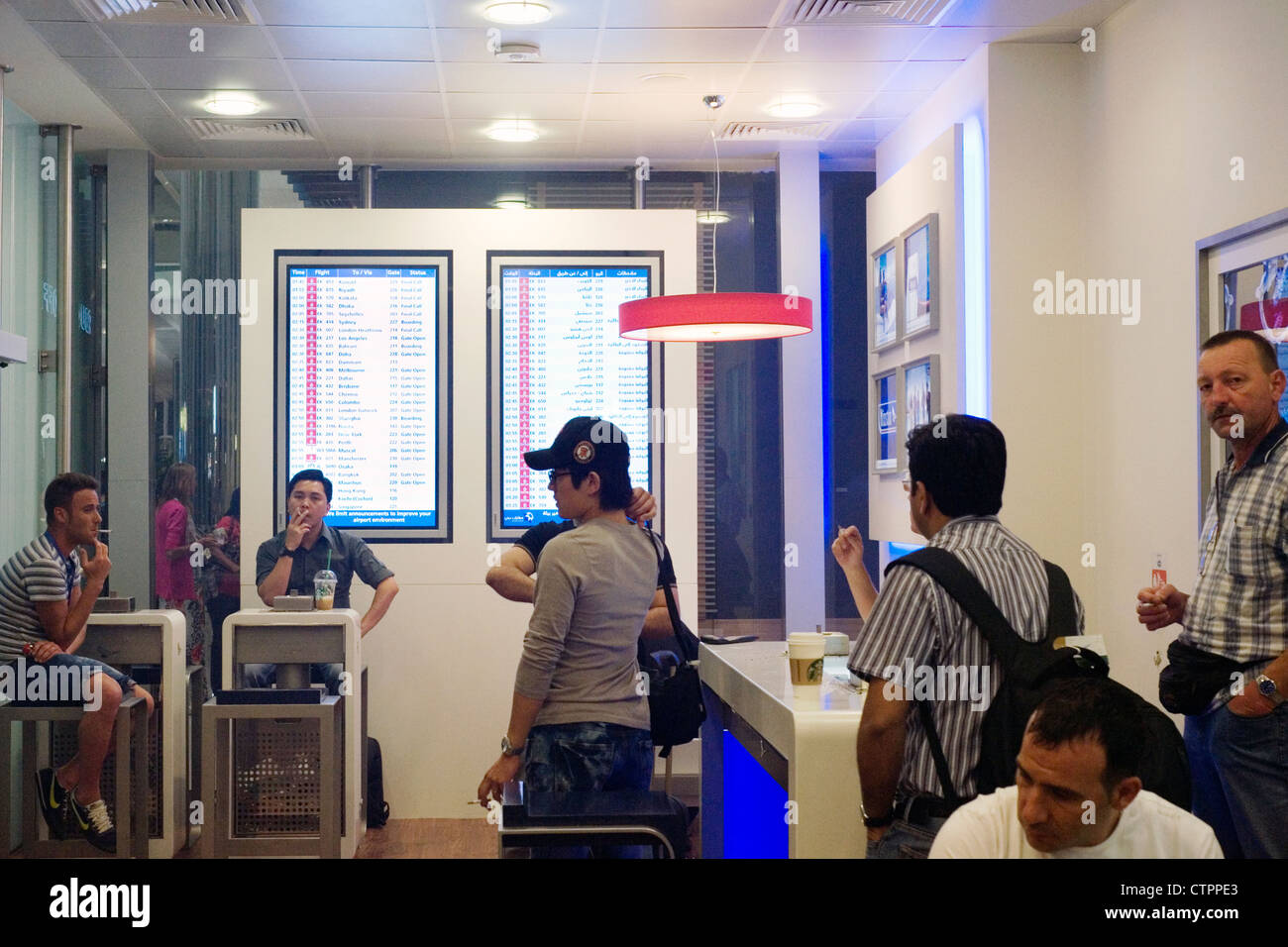 Les passagers de l'air vous détendre avec des cigarettes dans l'un des nombreux fumeurs à l'aéroport international de Dubaï Banque D'Images