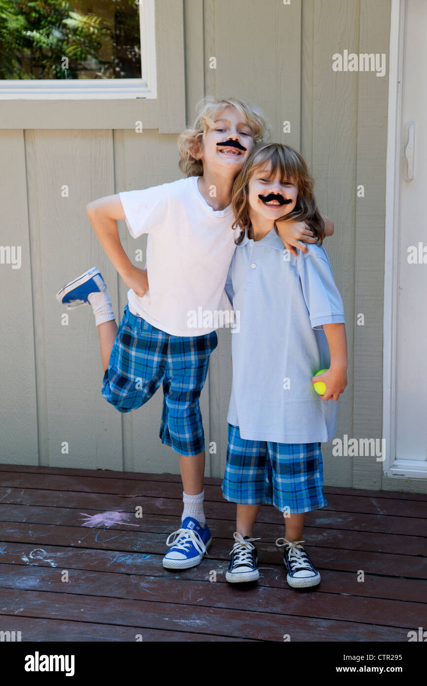 Un frère et une sœur sont debout ensemble portant de fausses moustaches. Banque D'Images