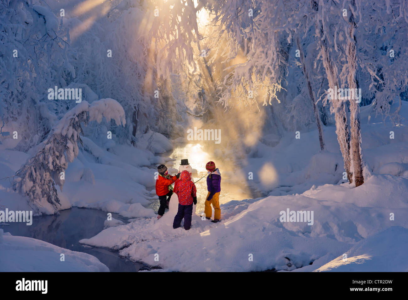 Trois enfants bonhomme de bâtiment à côté ruisseau dans la forêt couverte de givre Russian Jack Springs Park Anchorage Southcentral Alaska Banque D'Images