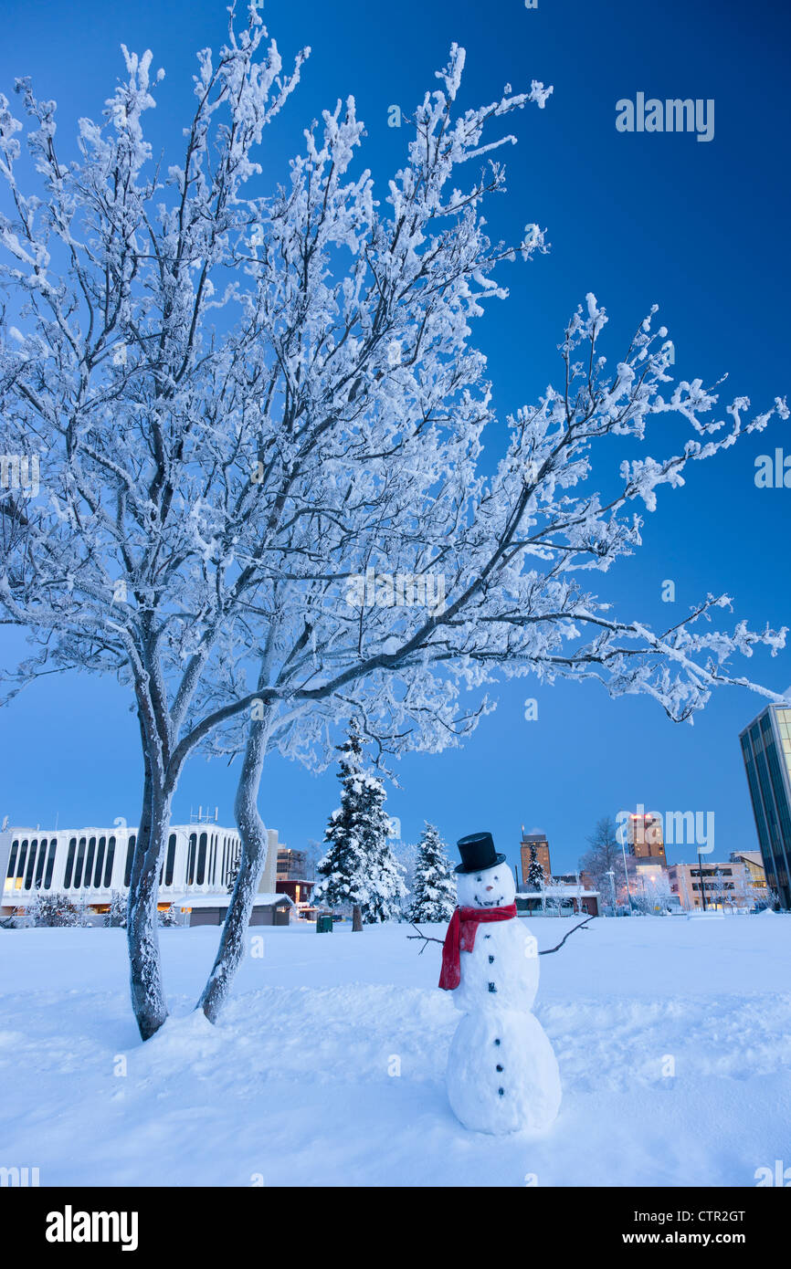 Le Snowman standing in Delaney Parkstrip centre d'Anchorage en arrière-plan hiver Winter twilight retouchées numériquement. Banque D'Images
