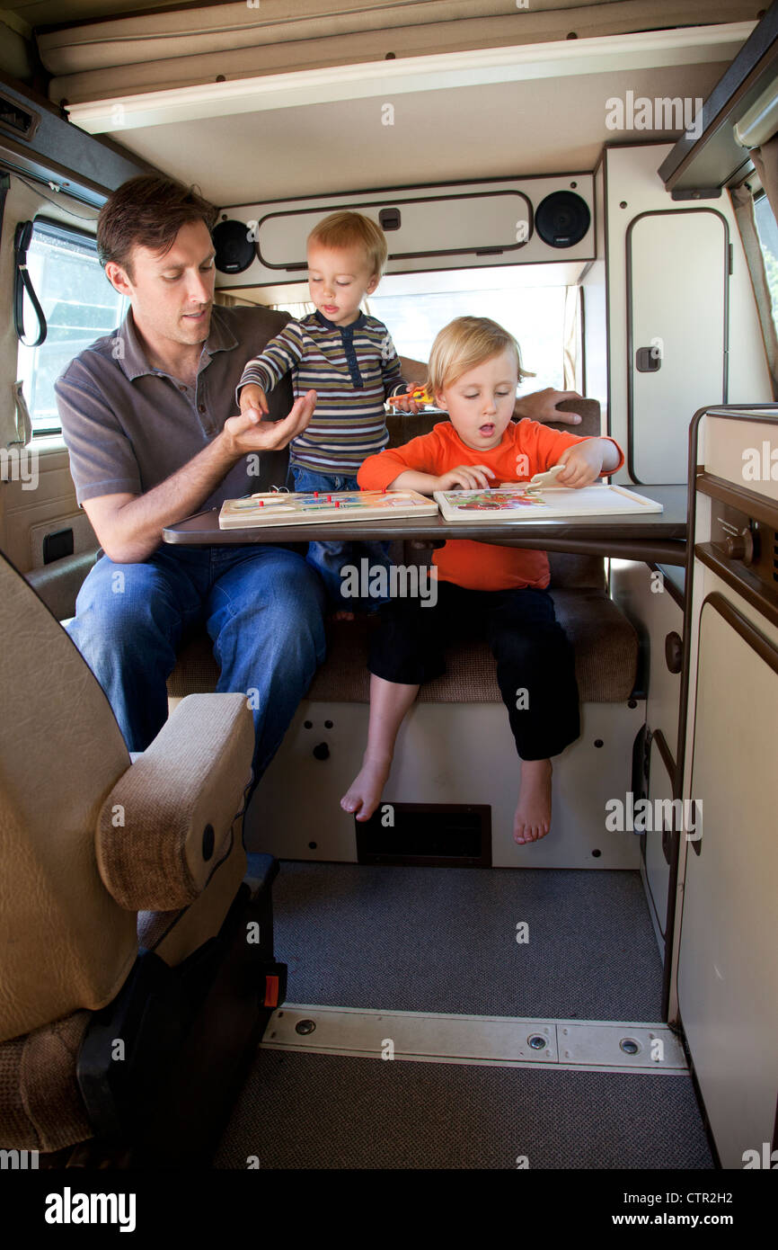 Un père et ses deux fils jouent dans l'arrière de leur camping-remorque. Banque D'Images