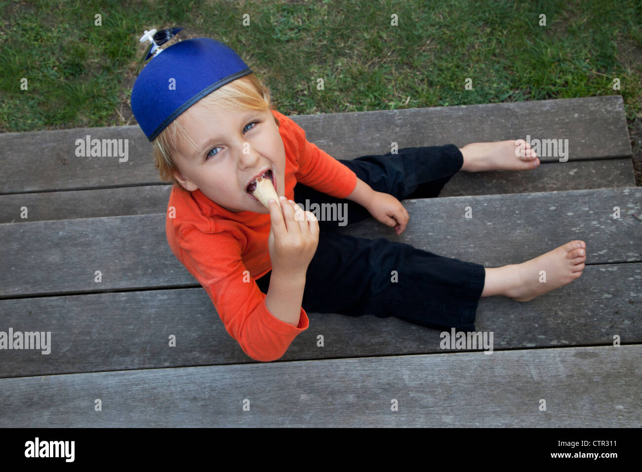 Un garçon dans une hélice hat est en train de manger un cornet de crème glacée. Banque D'Images
