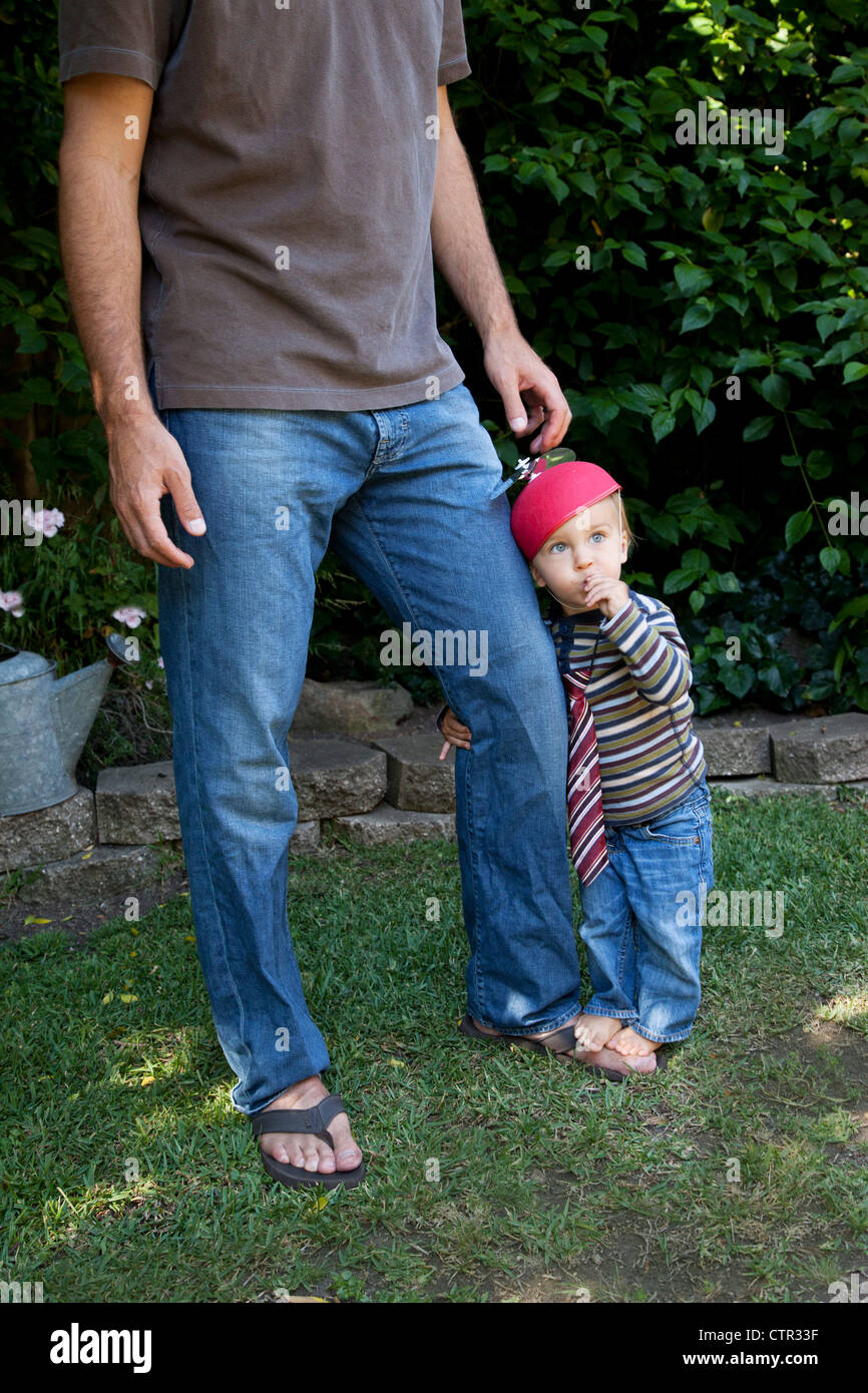 Un petit garçon est hugging son père du pantalon. Banque D'Images