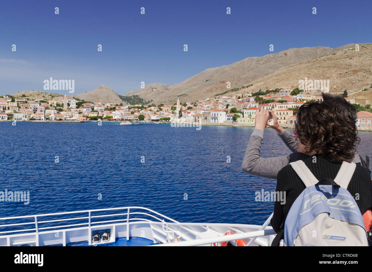 Un couple de prendre une photo sur la proue d'un traversier à l'approche de l'île de Halki du Dodécanèse, Grèce Banque D'Images