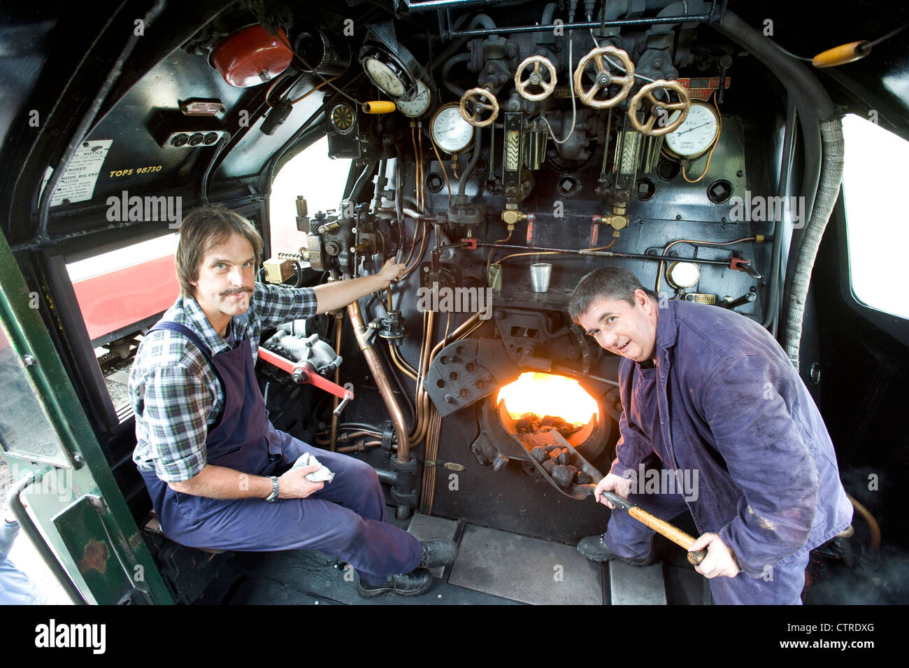 Conducteur de train et de pompier dans la cabine de locomotive à vapeur du sud ouest de la classe 'Pays' Pacifique 4-6-2 Nombre 34028 'Eddystone' sur le chemin de fer Swanage préservé dans le Dorset UK Banque D'Images
