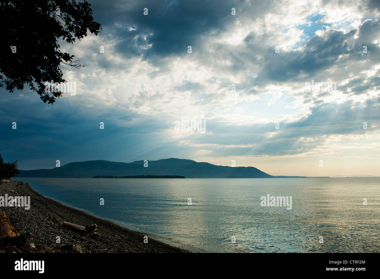 Coucher du soleil les faisceaux lumineux d'eau par storm clouds over Orcas Island dans la région de Puget Sound of western Washington, USA. Banque D'Images