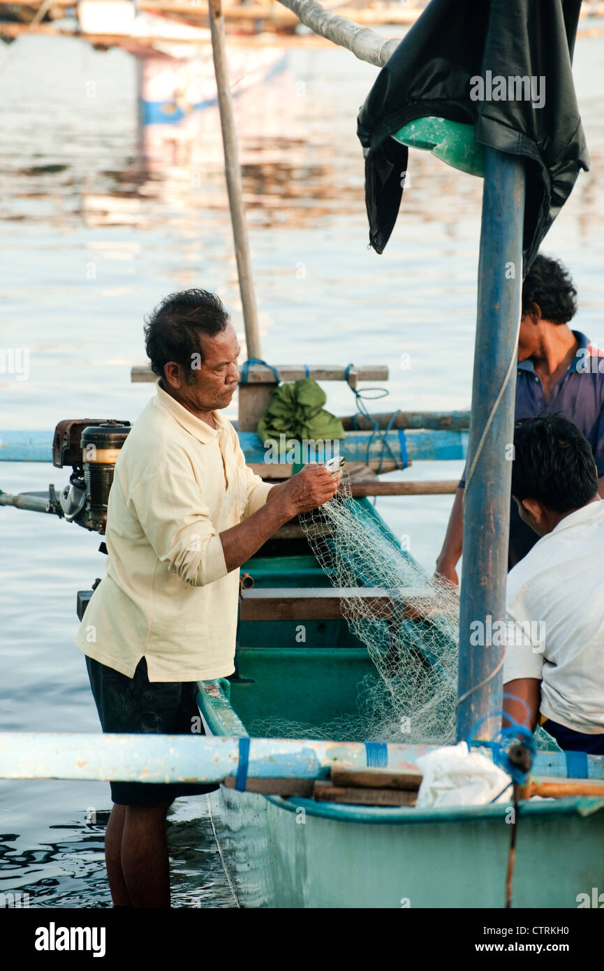 Un pêcheur dans le village balinais de Pemuteran, dans le nord-ouest de Bali décharge ses prises sur la plage après une nuit de pêche. Banque D'Images