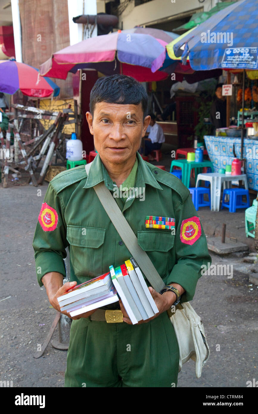 Ancien combattant en uniforme militaire birman vente de livres dans la rue à Yangon (Rangoon), la Birmanie (Myanmar). Banque D'Images