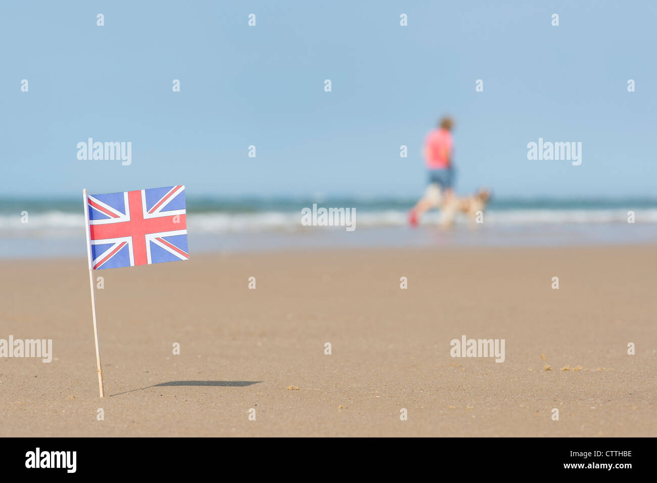Union Jack flag sur une plage avec un chien walker dans l'arrière-plan. Wells next the sea. Norfolk, Angleterre Banque D'Images
