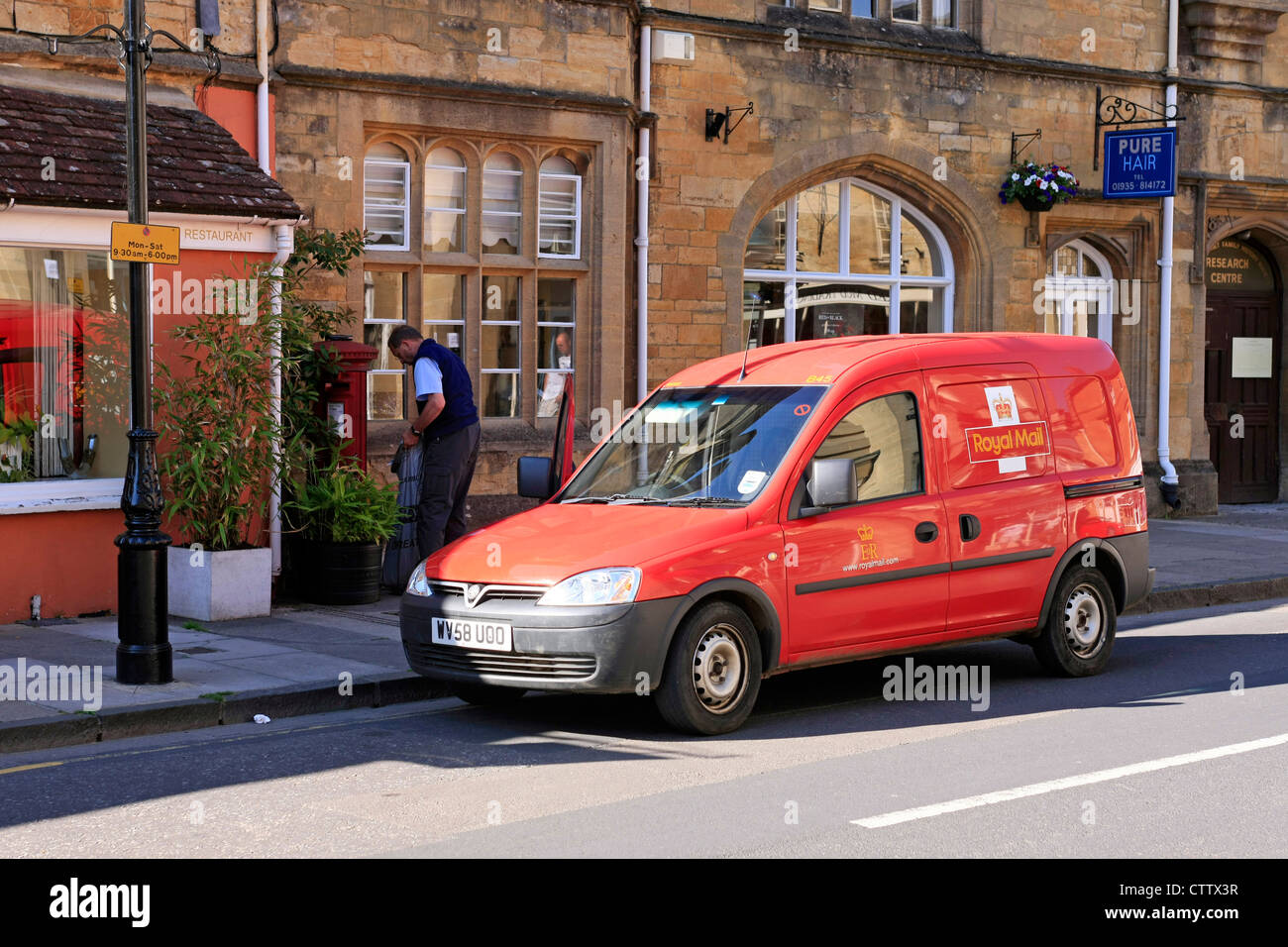 Royal Mail Postman sur sa route la collecte du courrier de cette boite aux lettres dans le Dorset Banque D'Images