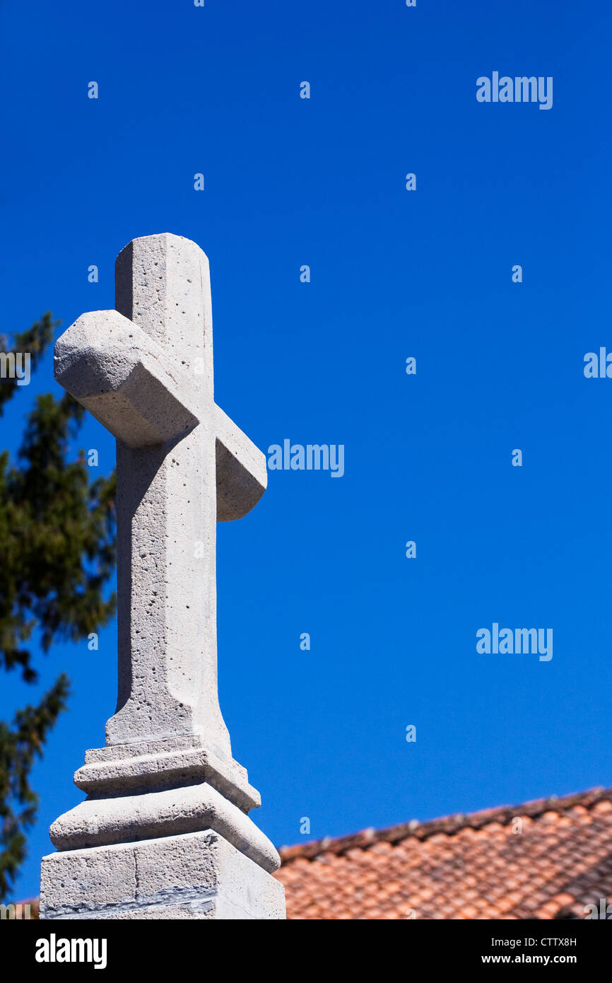Croix de pierre contre un ciel bleu dans un cimetière français. Banque D'Images