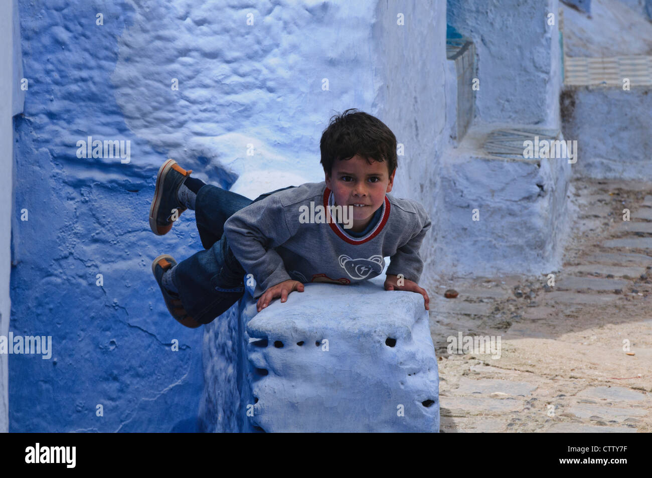 Enfant jouant dans le bleu de l'atmosphère ville de Chefchaouen, Maroc Banque D'Images