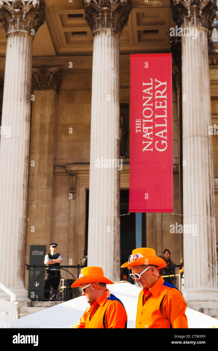 Deux hommes vêtus d'orange en face de la National Gallery à Trafalgar Square, dans le cadre du Holland House Festival 2010. Banque D'Images