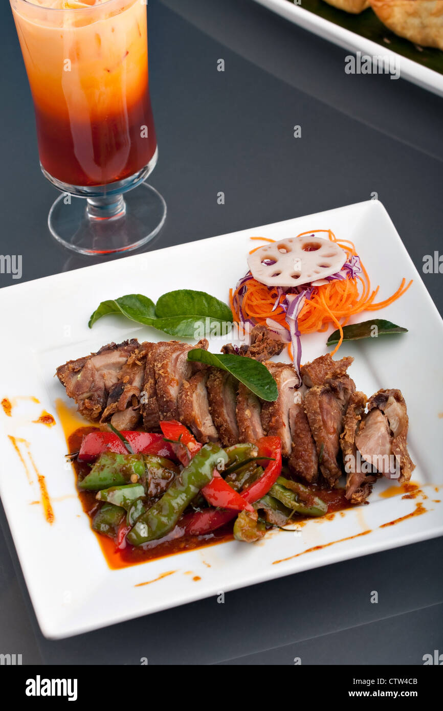 Très bien présenté un plat de style Thaï chili rôti de canard au basilic thaï et un mélange de légumes avec le thé glacé. Banque D'Images