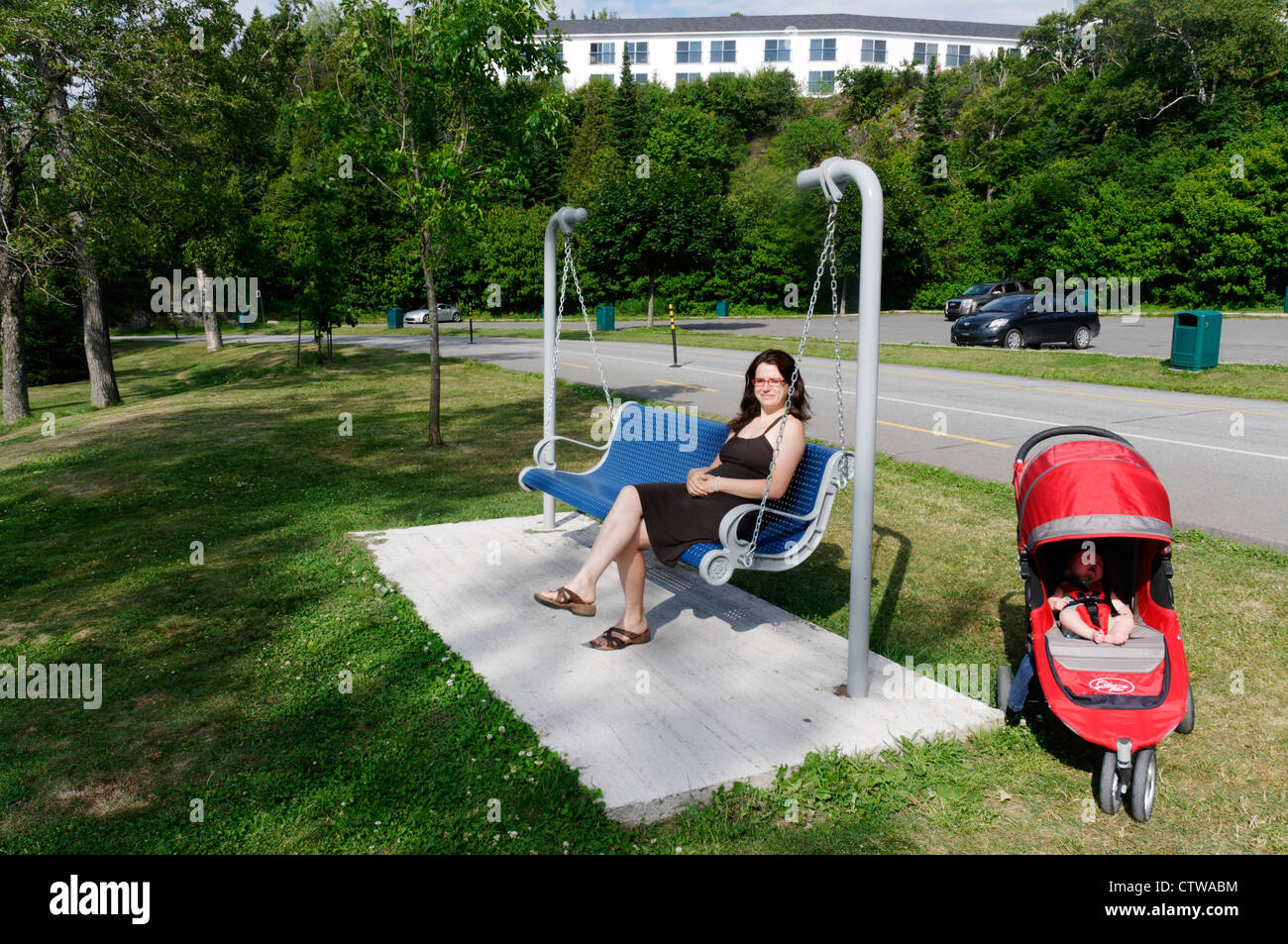 Une jeune femme était assise sur une balançoire banc public Banque D'Images