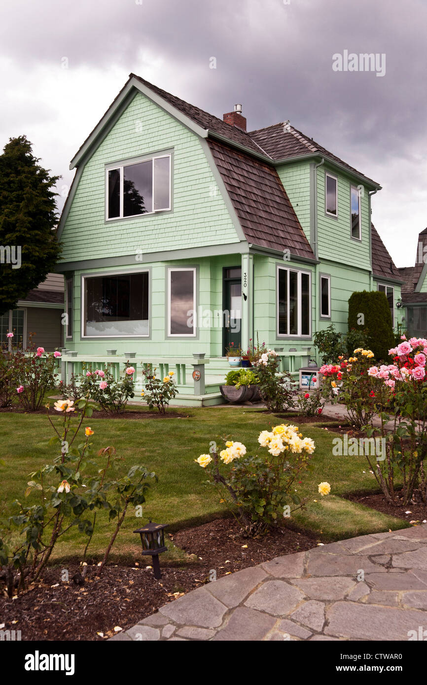 Vieille maison en bois peint vert pâle avec toit en mansarde et belle pelouse avec jardin de roses sur le front de mer d'Edmonds Washington Banque D'Images