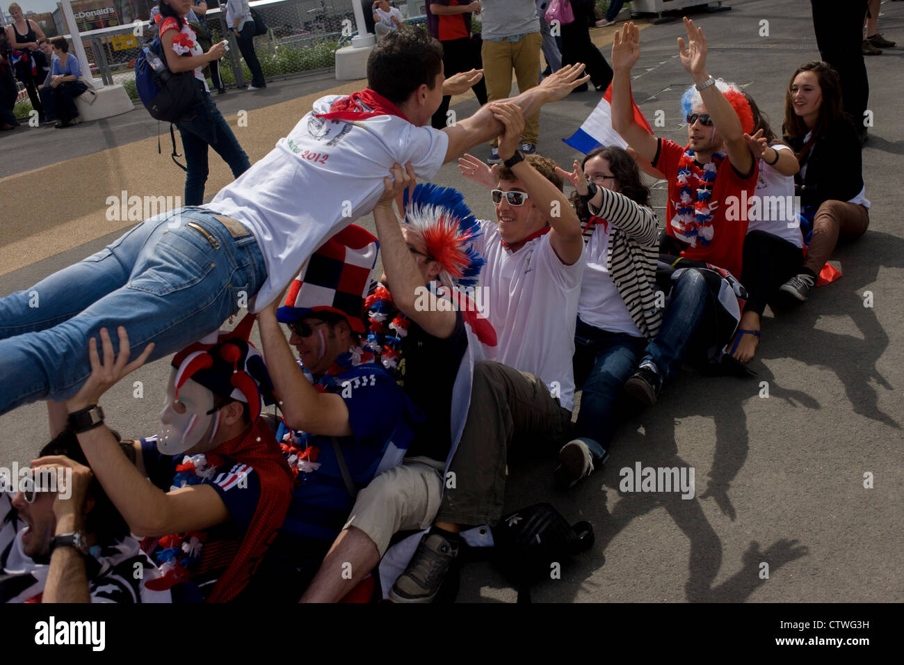 Les spectateurs français profitez de l'esprit des Jeux Olympiques et de la concurrence internationale dans le Parc olympique au cours de l'Jeux olympiques de 2012 à Londres. Les amateurs de sports de supporter le poids de leur ami et lui passe au-dessus. Ce terrain a été transformé pour devenir un 2,5 Km2 complexe sportif, une fois que les entreprises industrielles et maintenant le lieu de huit salles dont l'arène principale, centre aquatique et le vélodrome et le Village Olympique des athlètes. Après les Jeux Olympiques, le parc est d'être connu sous le nom de Queen Elizabeth Olympic Park. Banque D'Images