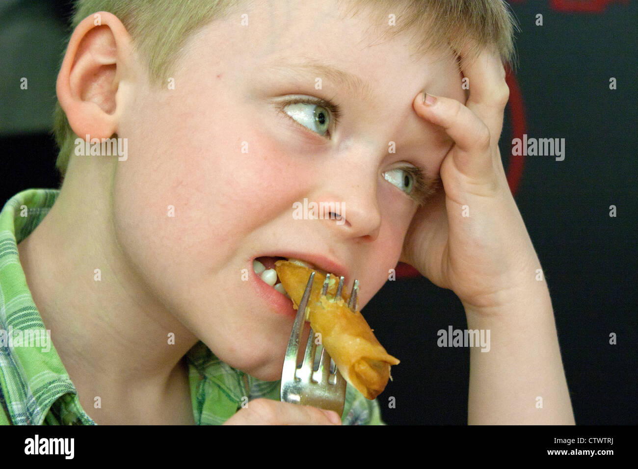 Portrait d'un jeune garçon de manger un rouleau de printemps Banque D'Images