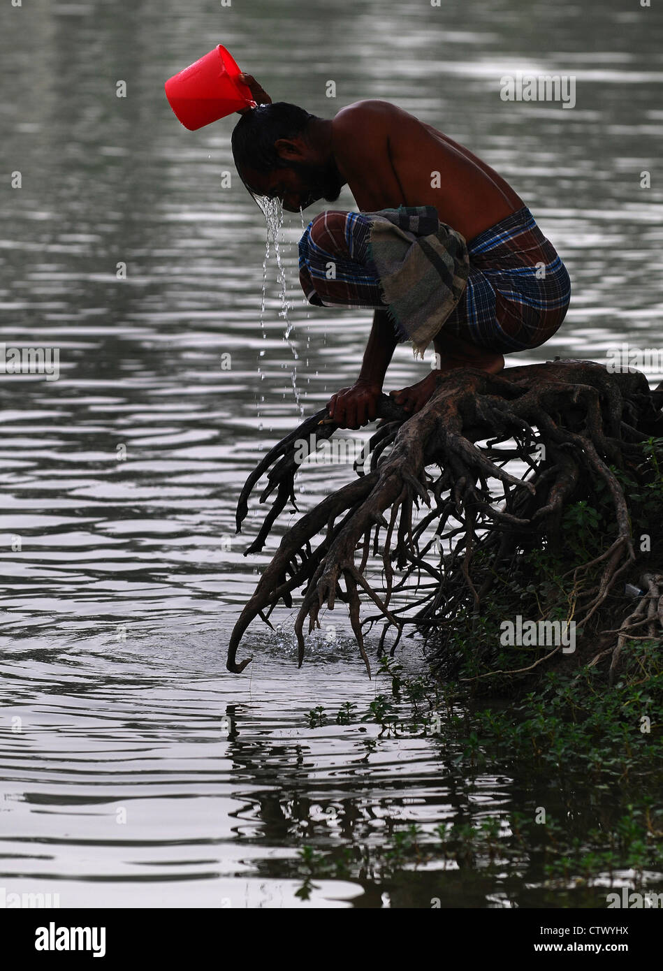L'homme de prendre une douche le long Shibsha River Bangladesh Banque D'Images