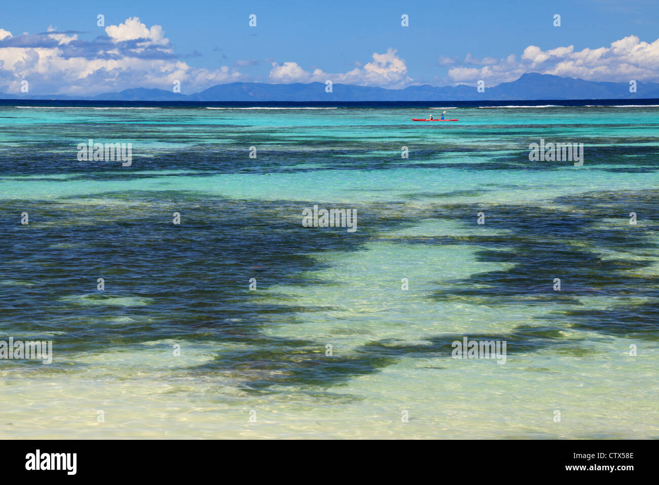 Deux personnes dans un kayak paddle rouge le long d'Anse Source d'argent sur La Digue aux Seychelles Banque D'Images