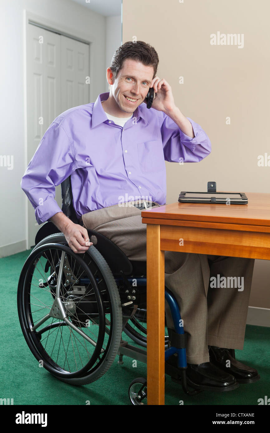 L'homme en fauteuil roulant avec de la moelle épinière en utilisant son téléphone cellulaire Banque D'Images