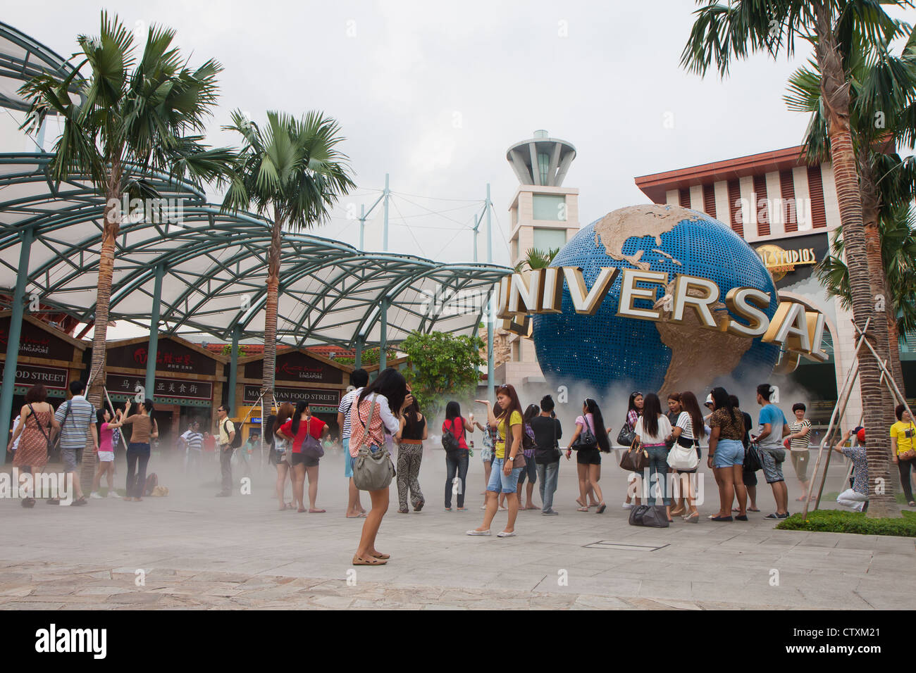 Singapour - Mars 2012 - Les touristes posant près de Universal Studios et le logo de marque déposée à Sentosa Resorts World, à Singapour. Banque D'Images