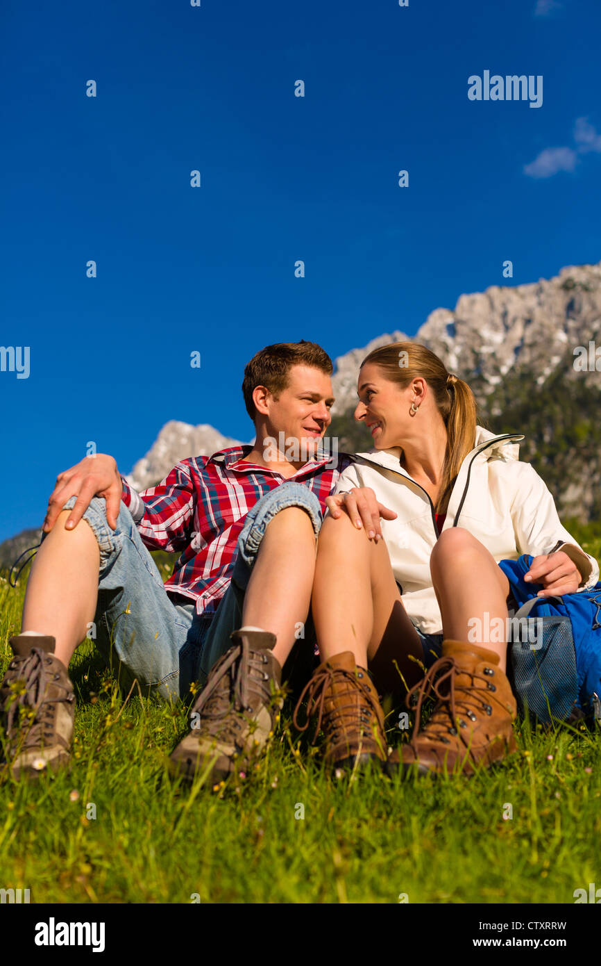 Couple heureux randonnées prenant une pause assis dans l'alp prairie avec vue panoramique Banque D'Images