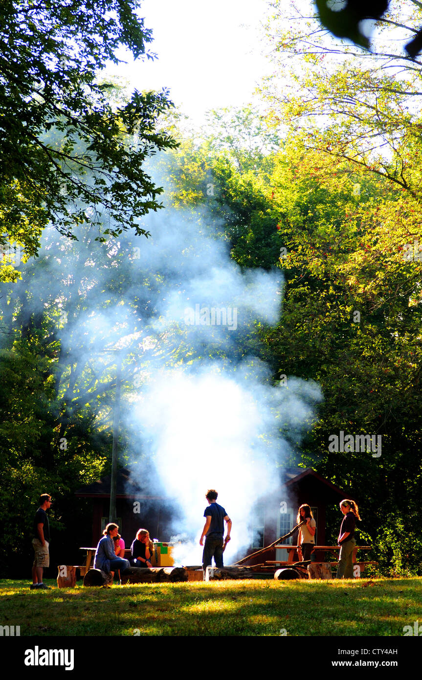 Les gens autour d'un feu de fumée dans une forêt d'été Banque D'Images
