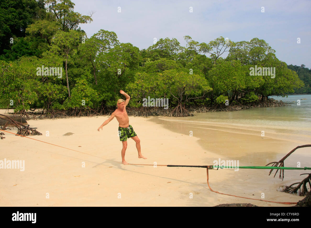 Homme marchant sur la corde raide à la plage, Ko Surin, Thaïlande Banque D'Images