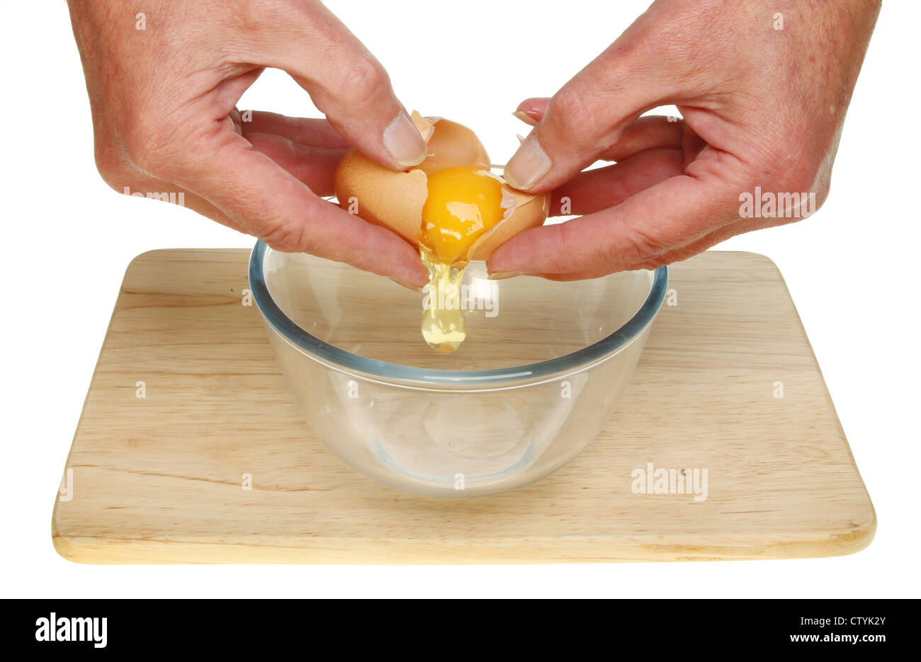 Libre d'une paire de mains fissurer un oeuf dans un bol en verre Banque D'Images