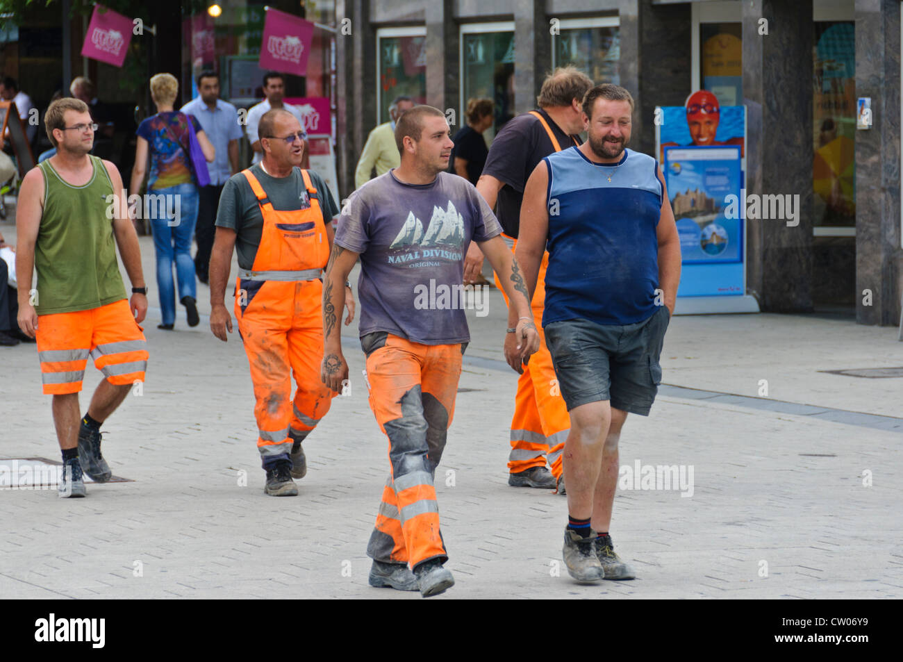 Un groupe de collègues travailleurs de la construction en couleur de signalisation orange vêtements de marche dans la zone piétonne de Heilbronn Allemagne Banque D'Images