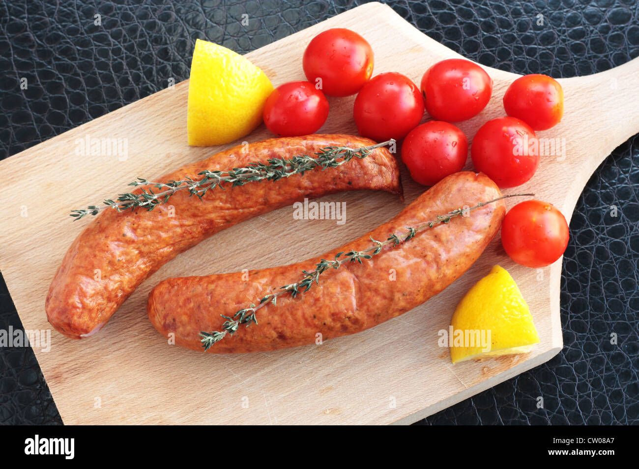 Les saucisses avec les tomates cerise, citron et thym Banque D'Images
