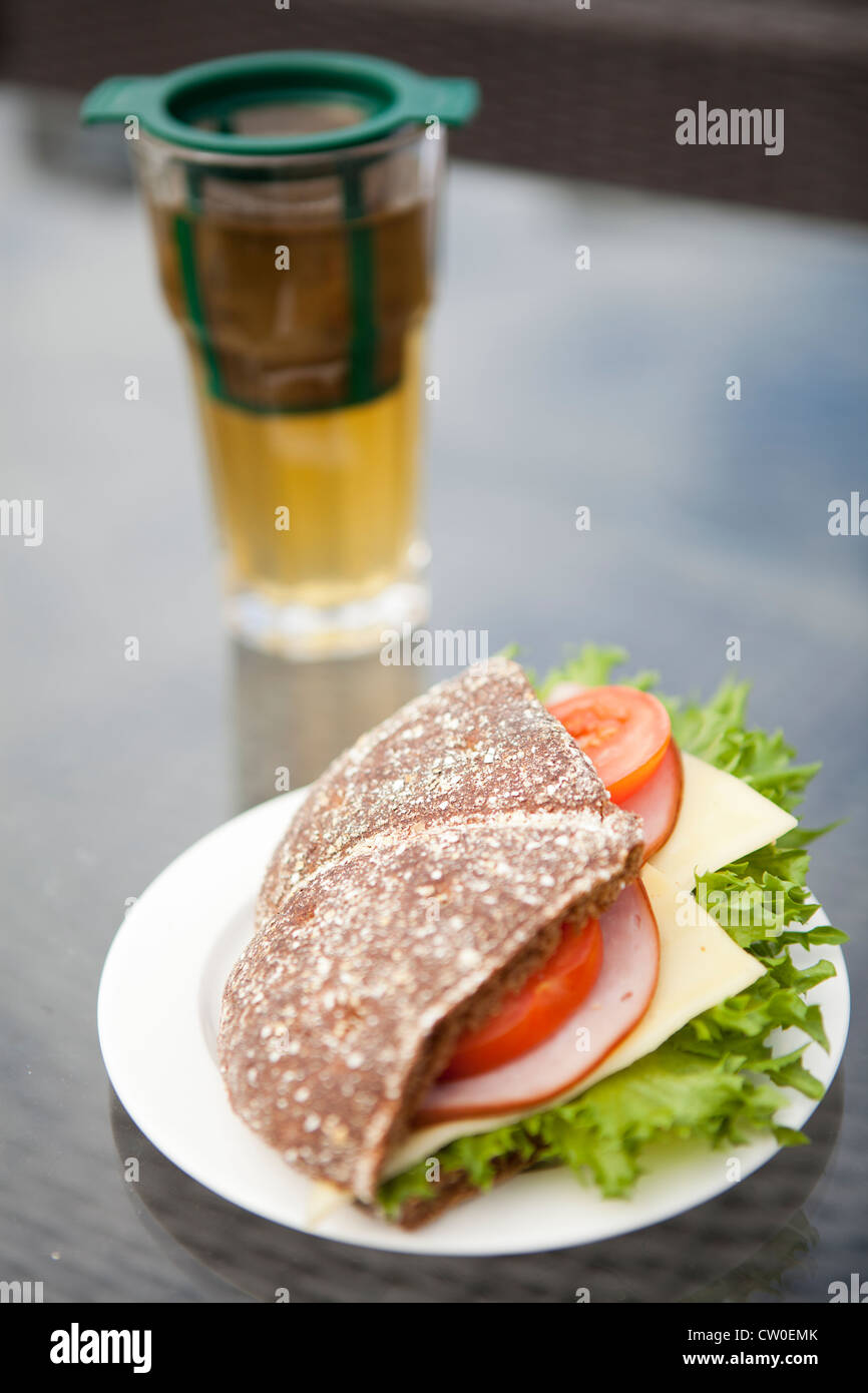 Close-up d'un jambon, fromage et tomate sandwich fait avec du pain de seigle. Verre de thé vert sur l'arrière-plan Banque D'Images