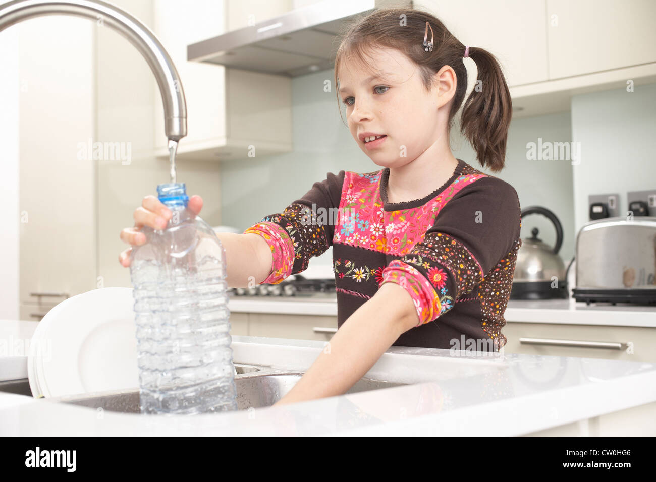 Fille de remplir la bouteille d'eau dans la cuisine Banque D'Images