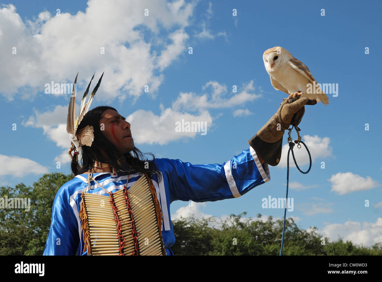 Un homme posant en Lakota (sioux) traditionnelle robe avec une chouette effraie. Banque D'Images