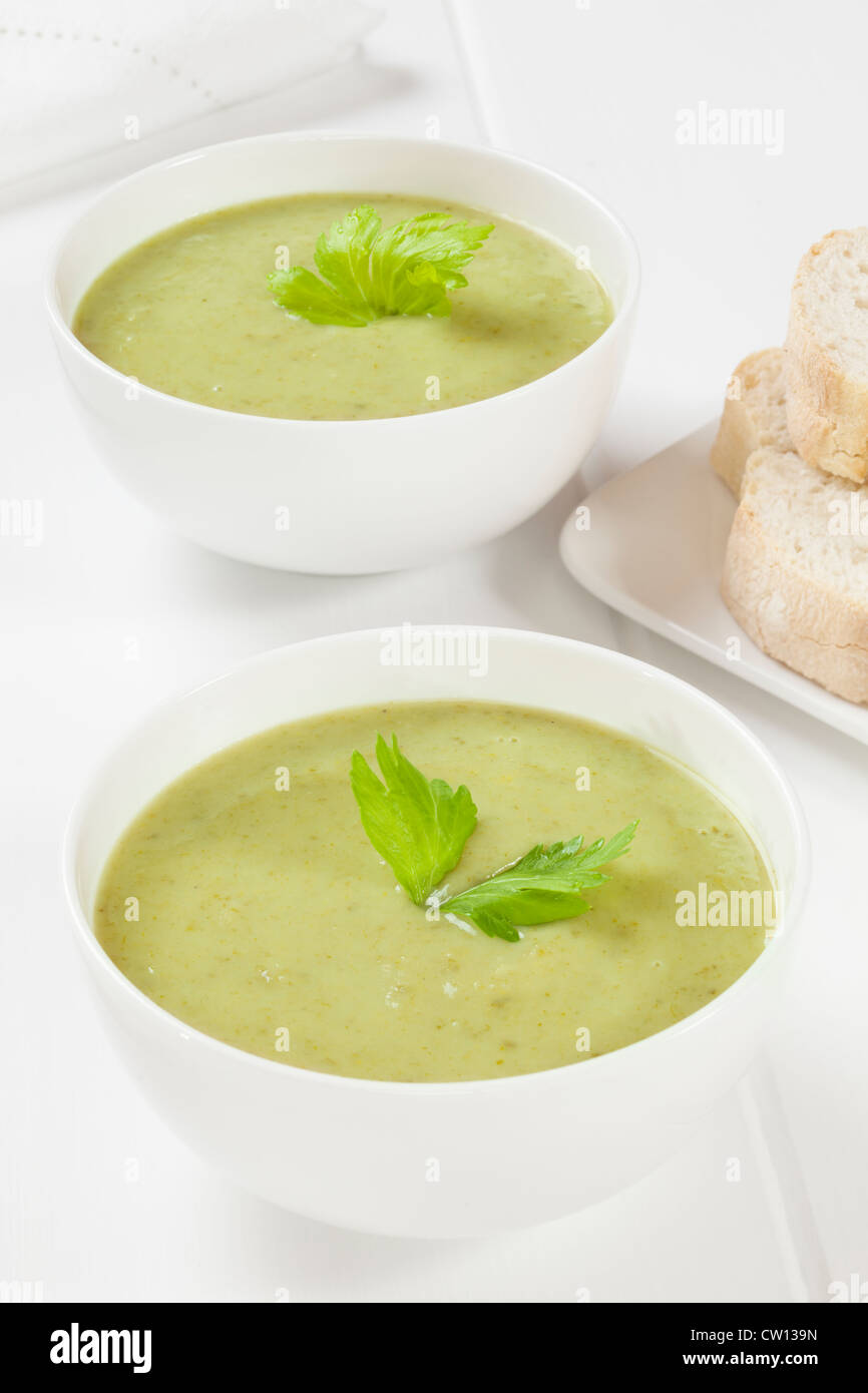 Deux bols de soupe de céleri crémeuse avec une garniture de feuilles de céleri, servi avec du pain croustillant. Banque D'Images