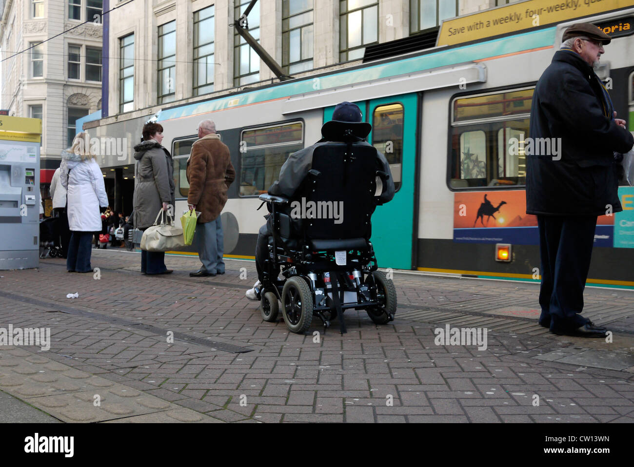 Homme handicapé sur un scooter de mobilité et d'autres passagers en attente à bord du tramway métro dans le centre-ville de Manchester UK. photo DON TONGE Banque D'Images