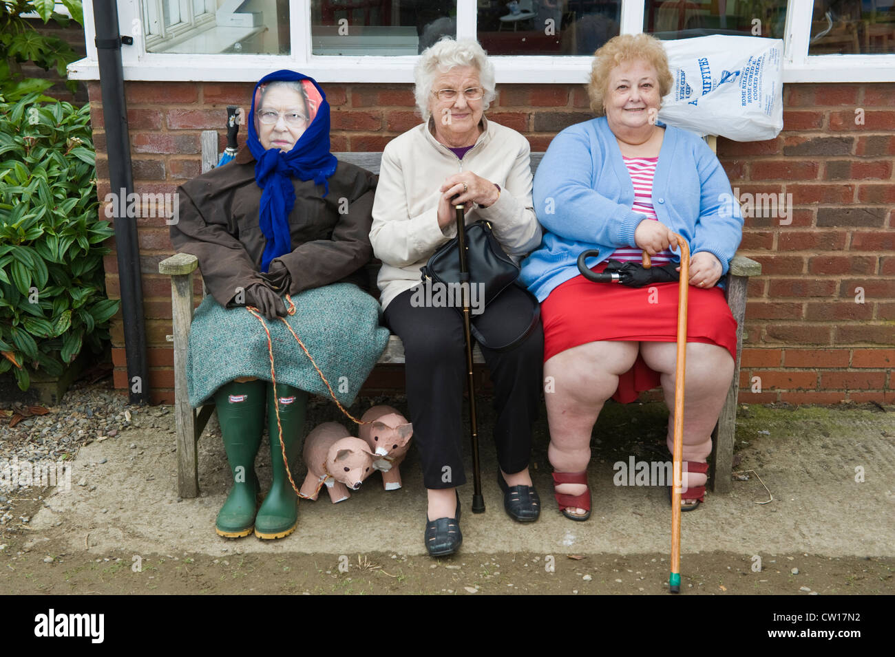 Effigie de la Reine s'assit sur un banc avec deux dames âgées au cours de la Journée de l'épouvantail dans village de Brampton Bryan Herefordshire Angleterre UK Banque D'Images