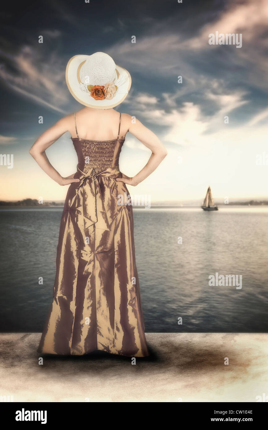 Une femme dans une élégante robe vintage sur la rive d'un lac Banque D'Images