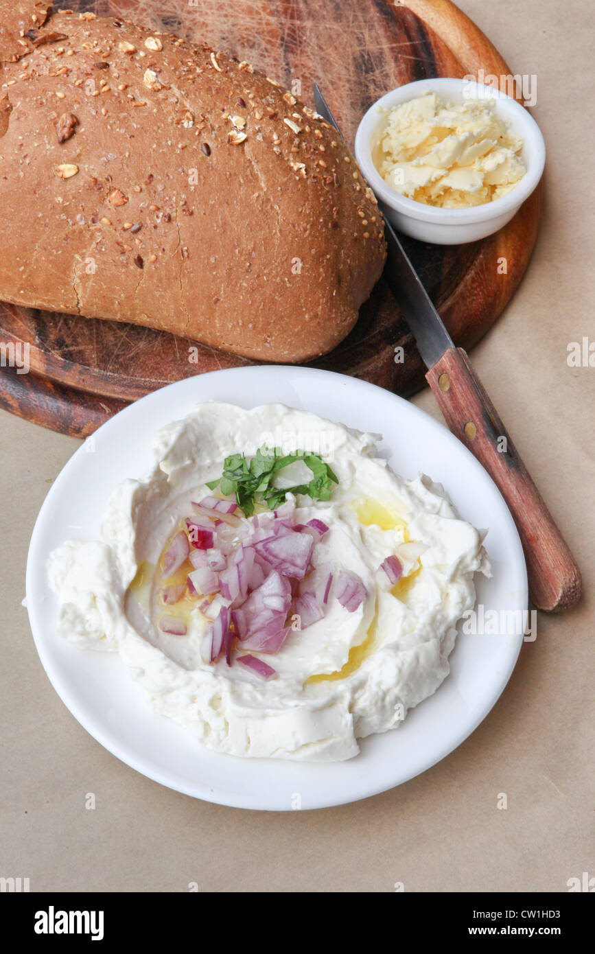 Labneh (fromage yaourt libanais fabriqués à partir de lait de vache) servi avec de l'huile d'olive, l'oignon et le pain et beurre Banque D'Images