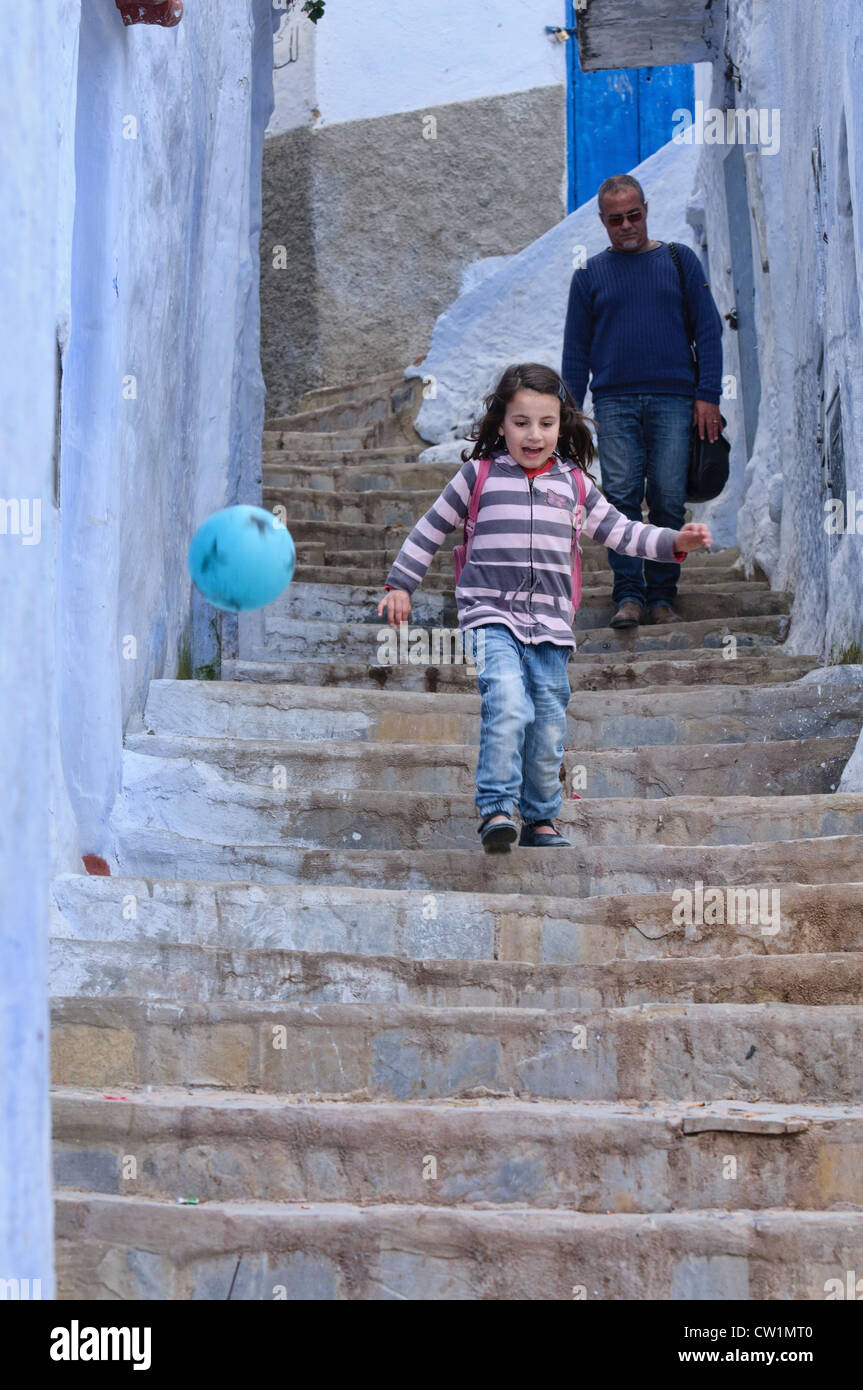 Enfant jouant dans le bleu de l'atmosphère ville de Chefchaouen, Maroc Banque D'Images
