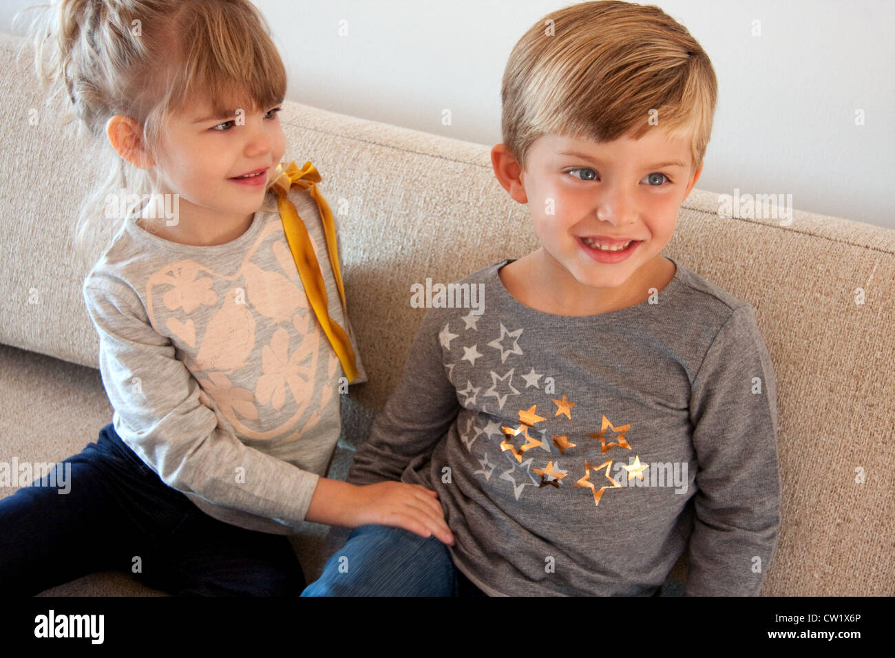 Deux enfants smiling blonde sur un canapé Banque D'Images